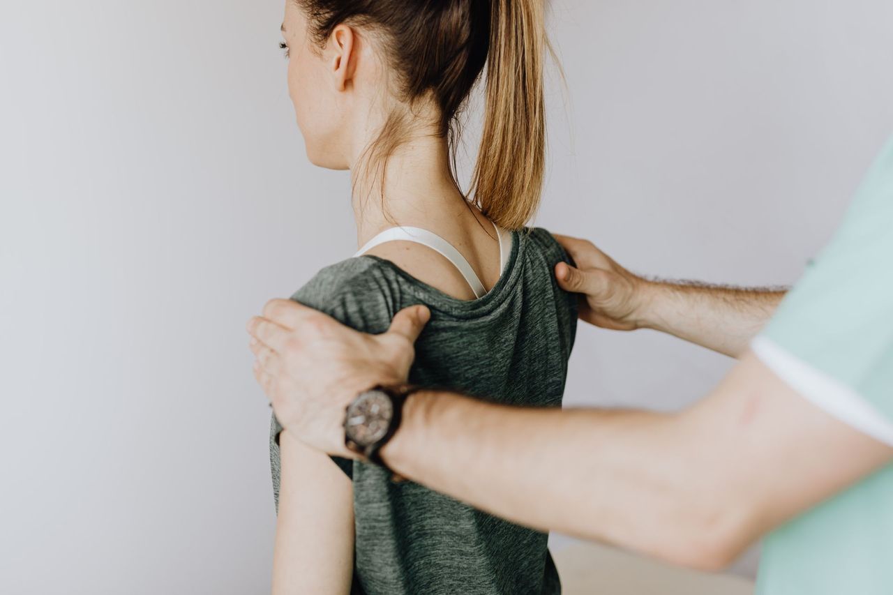 A chiropractor assessing a patient's shoulder and upper back alignment