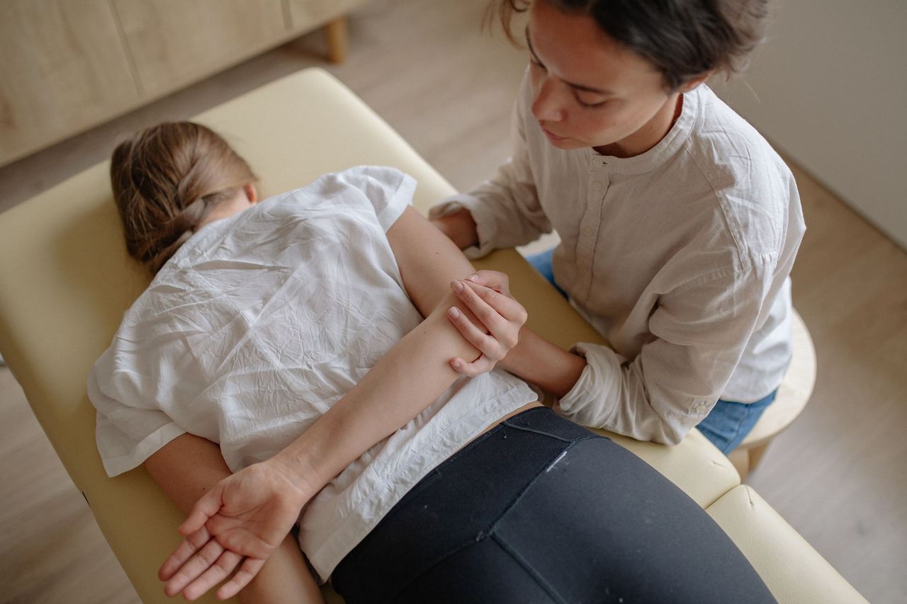 Close-up of a practitioner guiding a patient's arm through a mobilisation technique