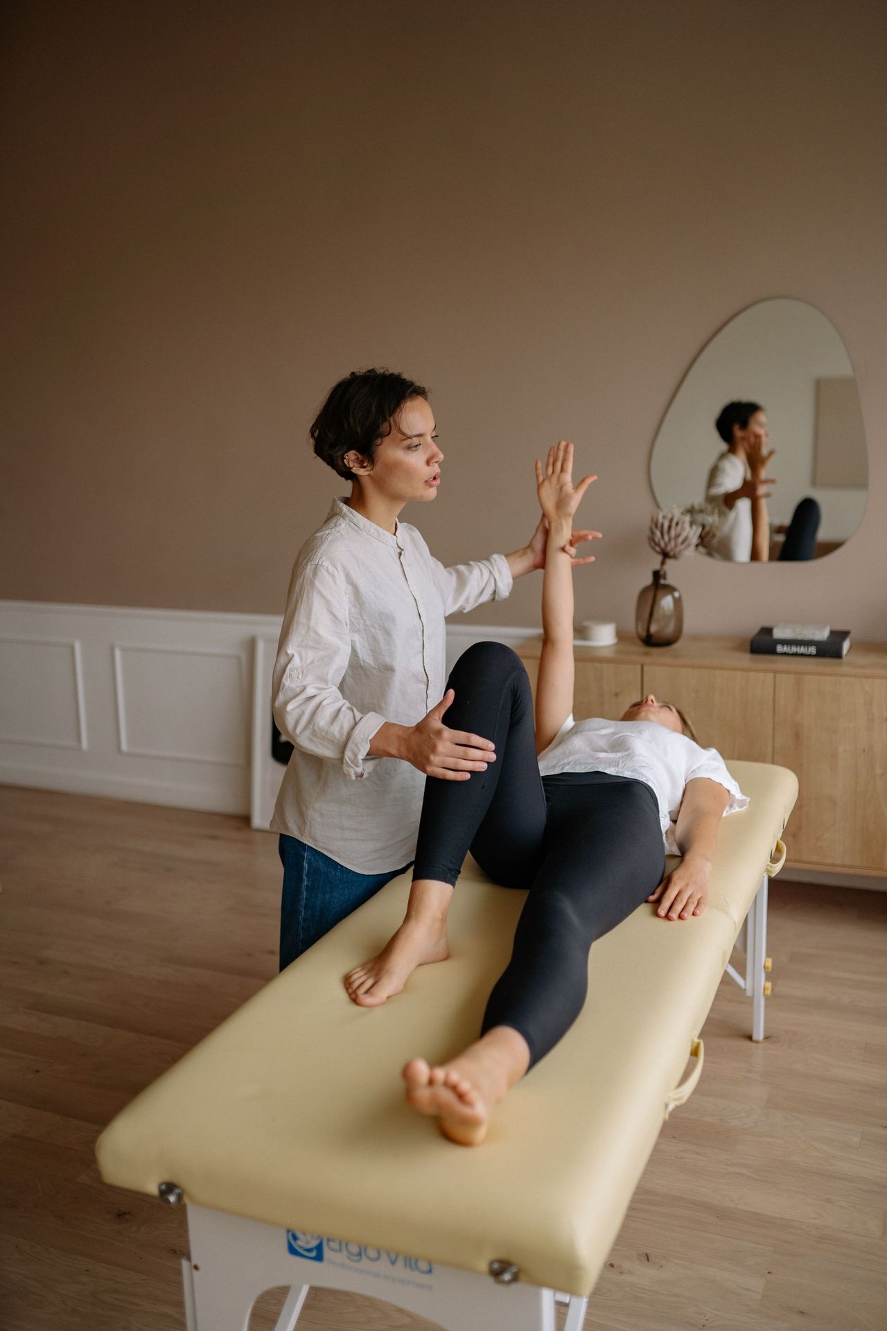 A practitioner assessing a patient's hip and leg movement on a treatment table
