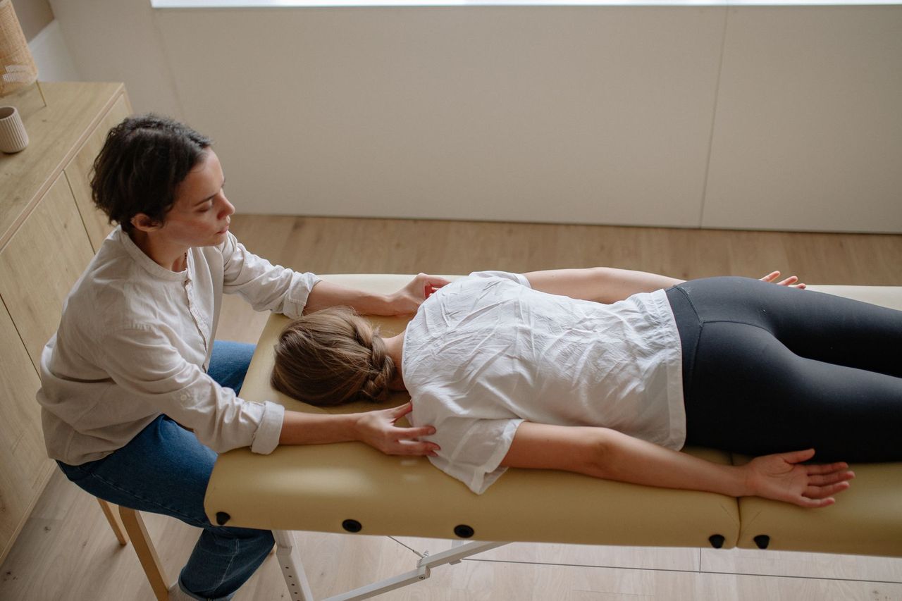 A chiropractor performing a gentle spinal mobilisation on a patient lying on a treatment table